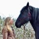 ME/CFS Awareness. Stacey Couch standing and looking at her black Friesian Percheron horse named Isabeau.